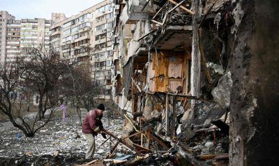 TOPSHOT - A man clears debris at a damaged residential building at Koshytsa Street, a suburb of the Ukrainian capital Kyiv, where a military shell allegedly hit, on February 25, 2022. - Russian forces reached the outskirts of Kyiv on Friday as Ukrainian President Volodymyr Zelensky said the invading troops were targeting civilians and explosions could be heard in the besieged capital. Pre-dawn blasts in Kyiv set off a second day of violence after Russian President Vladimir Putin defied Western warnings to unleash a full-scale ground invasion and air assault on Thursday that quickly claimed dozens of lives and displaced at least 100,000 people. (Photo by Daniel LEAL / AFP)